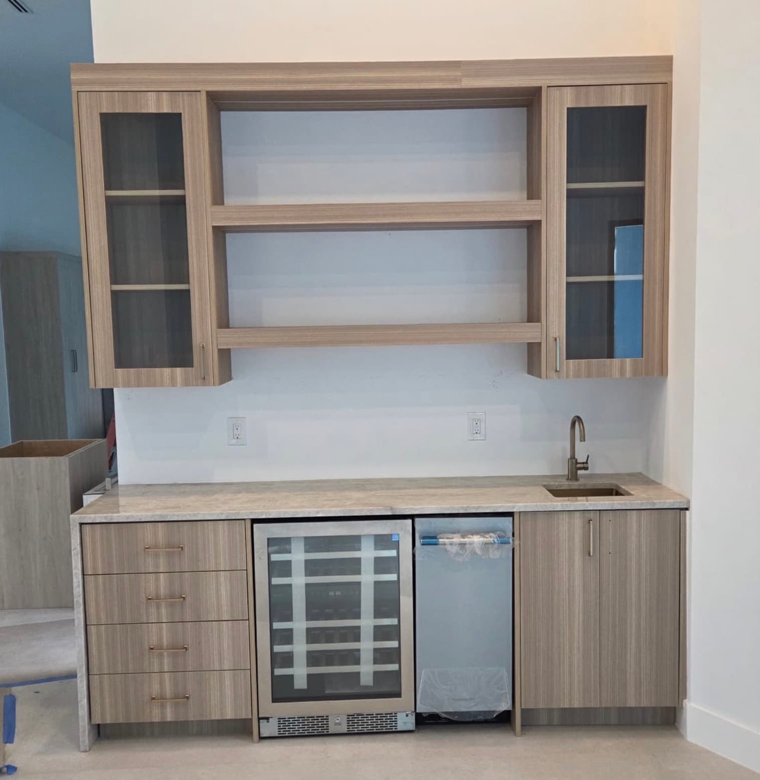 Wet bar cabinetry with built-in wine refrigerator installed by COPLASA